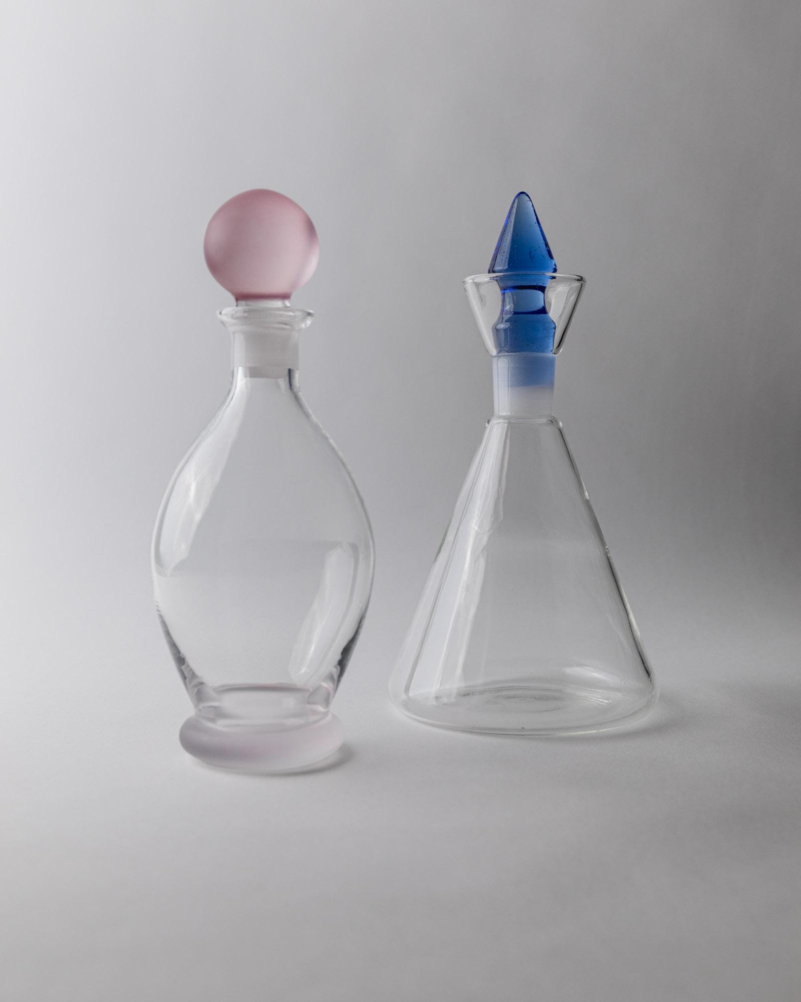 Vintage 1980s Glass Decanter Set of 2, Clear Glass with pink, blue Stoppers, Different Sculptural Shapes, Bar Accessory, Elegant Gift Idea_Bottega Jacobs