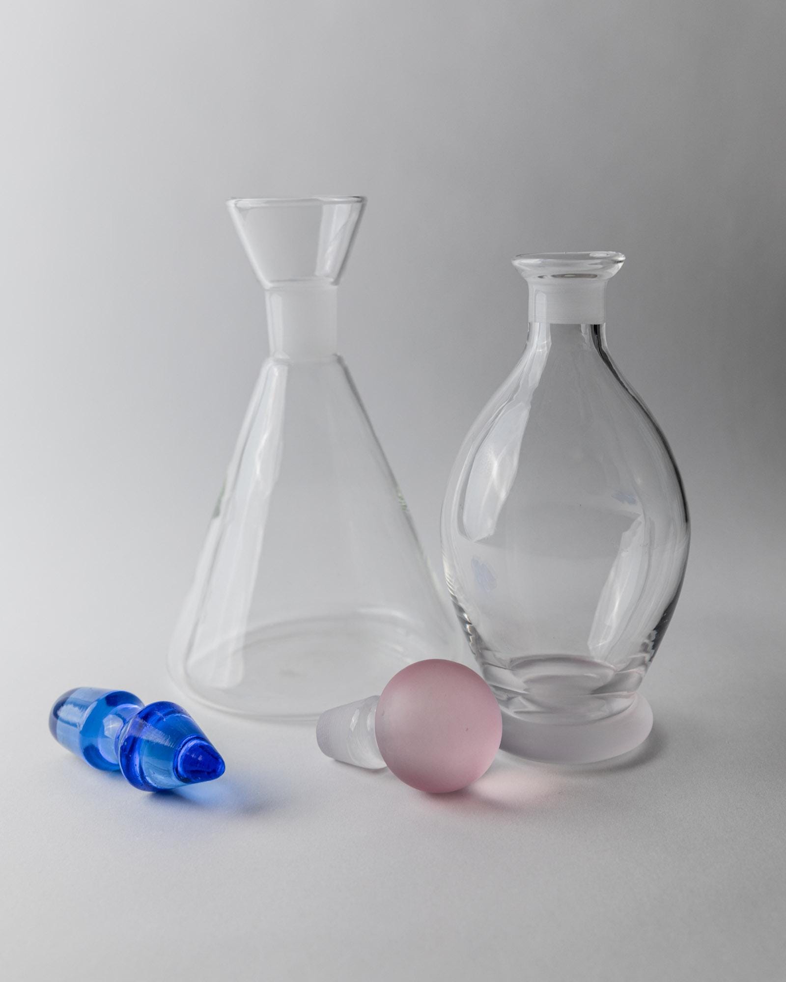Vintage 1980s Glass Decanter Set of 2, Clear Glass with pink, blue Stoppers, Different Sculptural Shapes, Bar Accessory, Elegant Gift Idea_Bottega Jacobs